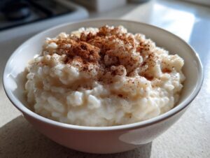 A close-up of a bowl of creamy rice pudding generously dusted with ground cinnamon.