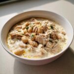 Close-up of a creamy bowl of crockpot white chicken chili with shredded chicken and white beans.