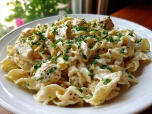 Close-up of creamy pasta with chicken chunks coated in a rich garlic parmesan sauce and topped with fresh parsley.