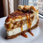 A rich slice of apple pie cheesecake layered with spiced apples and drizzled heavily with caramel sauce.