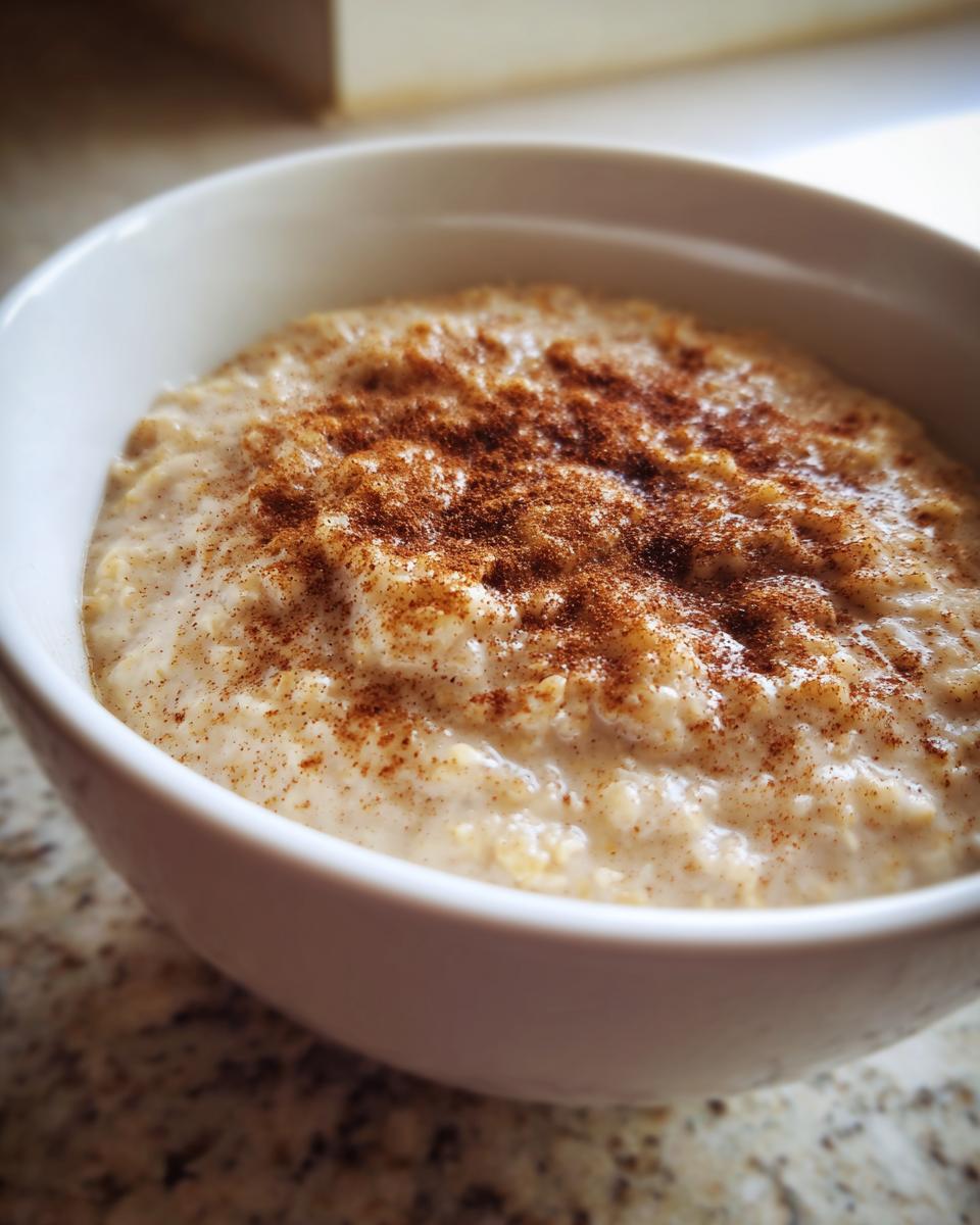 Close-up of creamy banana oatmeal in a white bowl, generously topped with ground cinnamon.