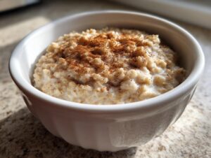 Close-up of creamy banana oatmeal in a white bowl, generously sprinkled with cinnamon.