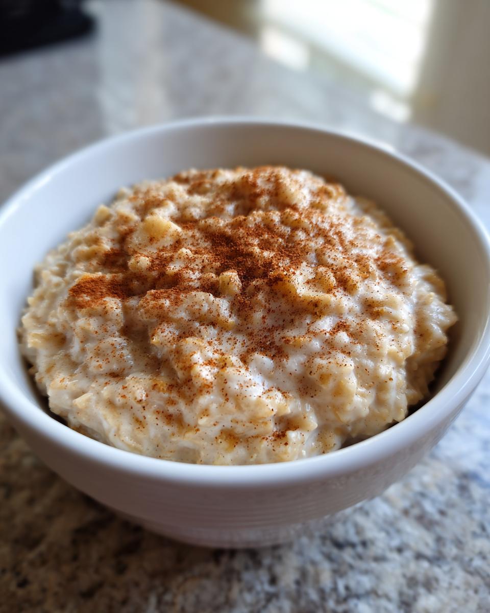 Close-up of creamy banana oatmeal in a white bowl, generously topped with ground cinnamon.