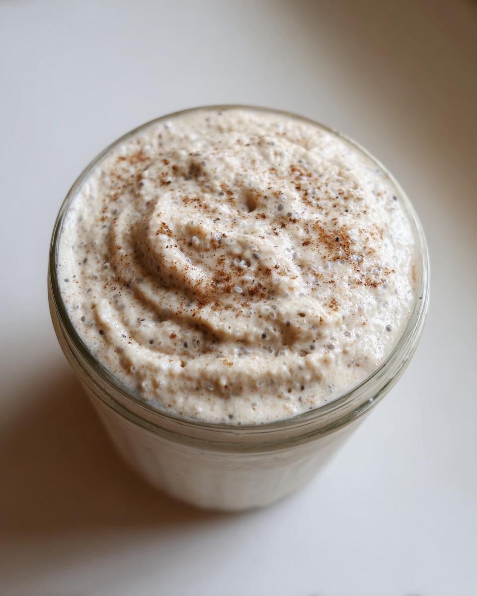 Overhead view of creamy chia seed pudding topped with cinnamon in a glass jar.
