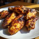 Close-up of several perfectly cooked, crispy chicken wing pieces with a dark, caramelized glaze.