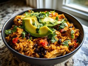Close-up of a delicious chicken burrito bowl topped with sliced avocado and fresh cilantro.