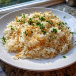 A serving of fluffy rice pilaf mixed with toasted vermicelli and topped with fresh chopped parsley on a white plate.