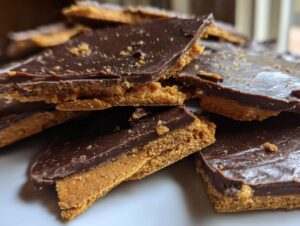 Close-up of stacked pieces of homemade graham cracker toffee with a thick chocolate topping.