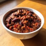 Close-up of a hearty bowl of rich, red crockpot chili loaded with ground meat and kidney beans.
