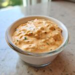 Close-up of creamy, orange-hued homemade big mac sauce with visible relish chunks in a small white and clear glass dipping bowl.