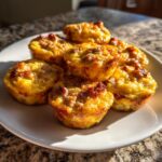A stack of golden brown, baked sausage egg bites piled high on a white plate, perfect for meal prep.