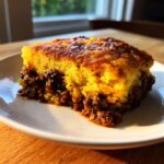 A close-up of a hearty slice of sloppy joe cornbread casserole showing the golden cornbread topping over the savory meat filling.