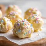 Close-up of white chocolate coated sugar cookie truffles topped with pastel sprinkles.